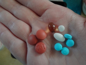 A hand holding 10 different pills