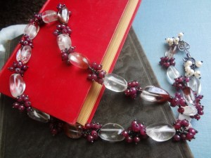 A long ruby and quartz necklace sitting on books
