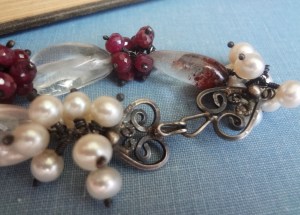 A blackened silver heart hook clasp surrounded by white pearls